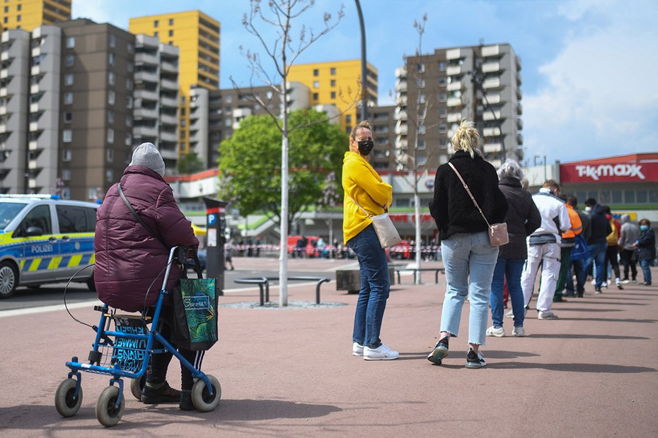 Menschen stehen in Köln-Chorweiler vor dem Impfbus Schlange