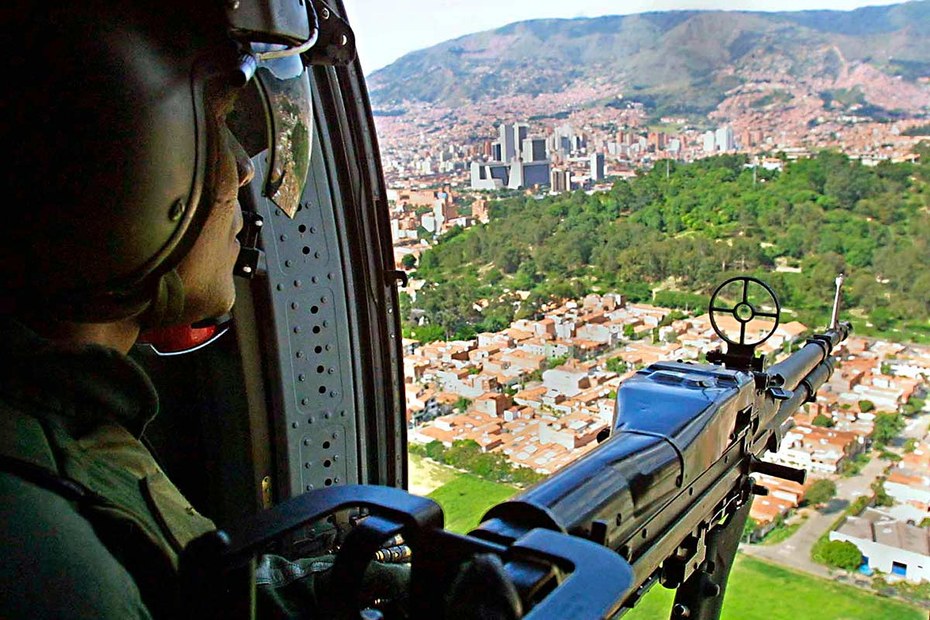Ein schwer bewaffneter Soldat fliegt im Jahr 2002 über die kolumbianische Stadt Medellín