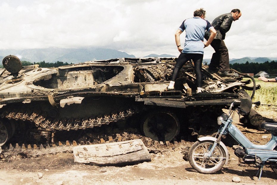 Slowenien, 1991: Männer begutachten ein zerstörtes Panzerfahrzeug