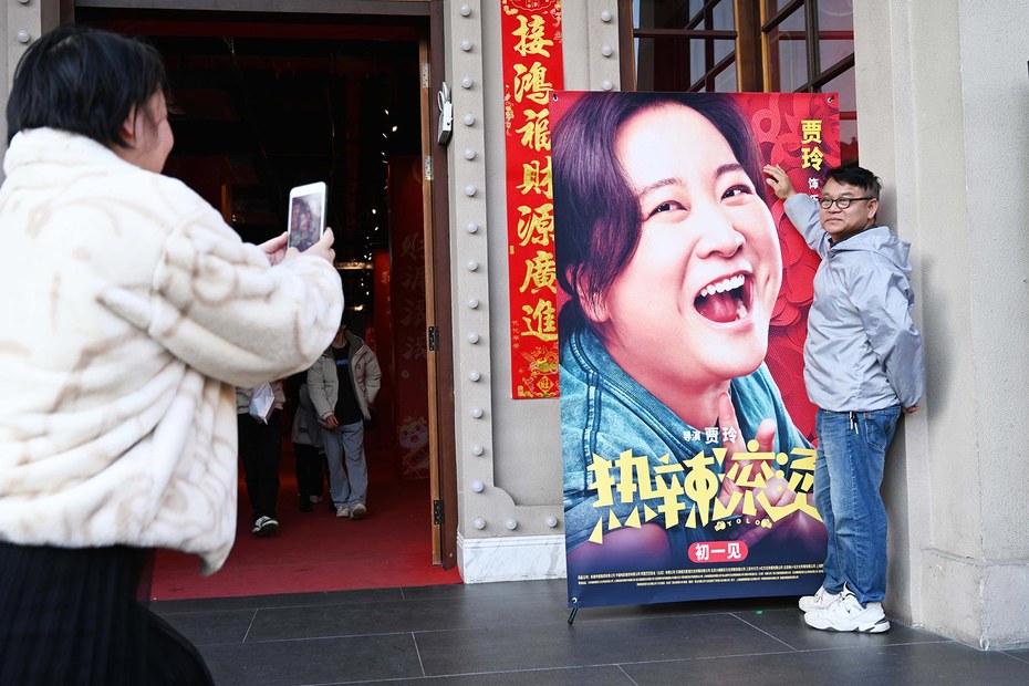 In der Millionenstadt Nanning posiert ein Mann zu Beginn des neuen Mondjahres des Drachens vor dem Filmplakat mit Regisseurin und Hauptdarstellerin Jia Ling.