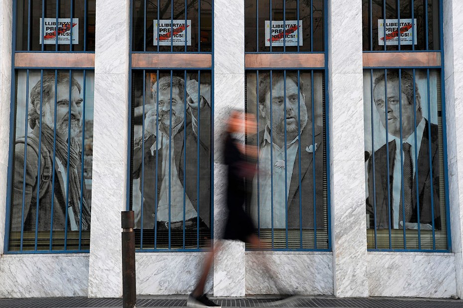 Eine Frau streift vier Bilder katalanischer Separatistenführer (v.l.n.r.): Jordi Cuixart, Jordi Sanchez, Oriol Junqueras und Joaquim Forn