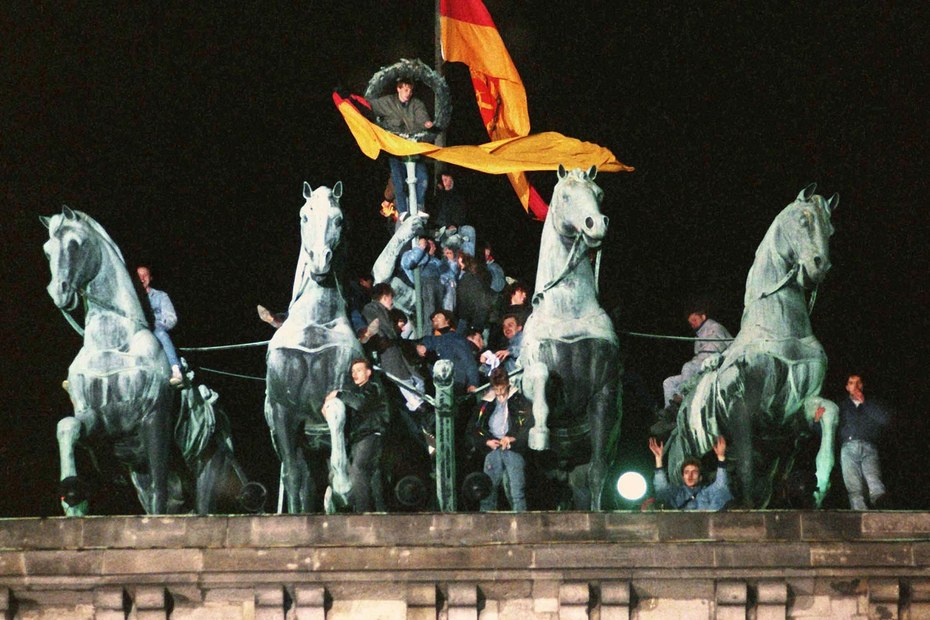 Bei der ersten gesamtdeutschen Silvesterfeier 1989 stürmt ein Partymob das Brandenburger Tor und zerstört die Quadriga