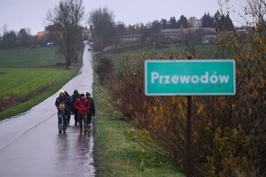 Polizeibeamte in Regenmänteln suchen die Umgebung nach der Explosion in Przewodów ab