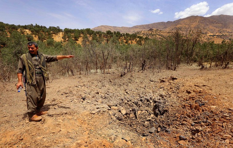 PKK-Kämpfer zeigt auf einen Granateinschlag in den Kandil-Bergen