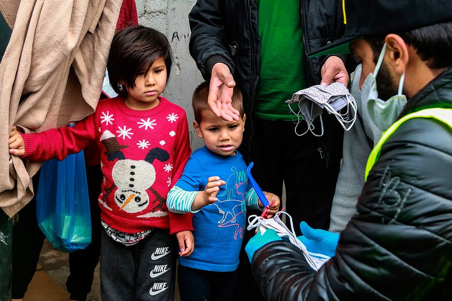 Mitglieder einer Nichtregierungsorganisation verteilen selbstgenähte Schutzmasken im Flüchtlingslager Moria
