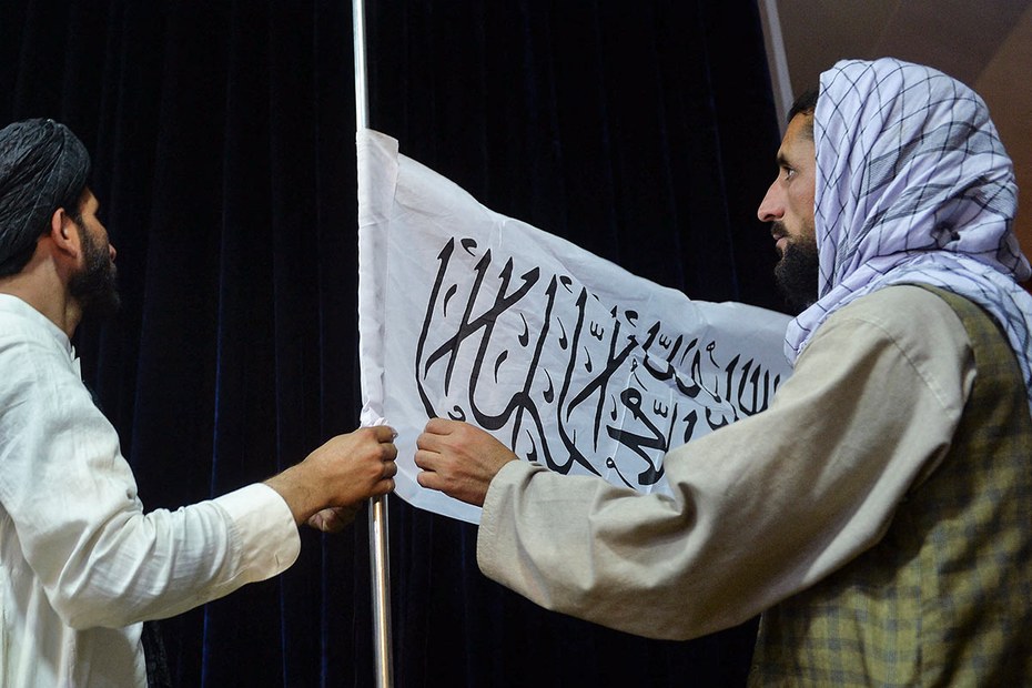 Kämpfer der Taliban richten die Flagge des „Emirats Afghanistan“ vor einer Pressekonferenz aus