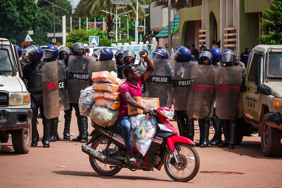 Ein Mann erhebt die Faust neben Polizisten, die eine Demonstration in Burkina Fasos Hauptstadt Ouagadougou begleiten