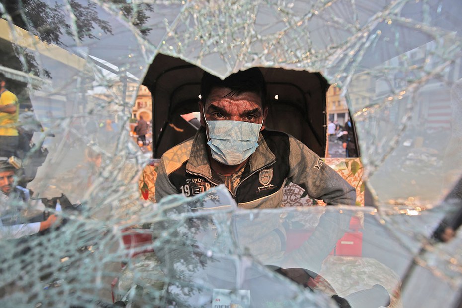 Ein irakischer Tuk Tuk-Fahrer hinter zerbrochener Windschutzscheibe