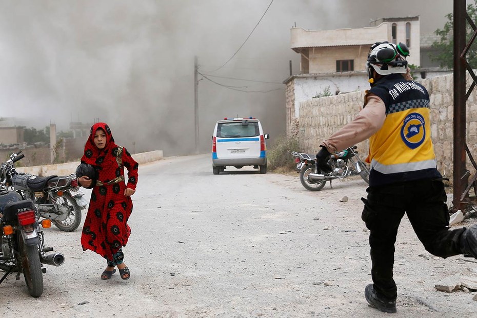 Ein syrisches Mädchen und ein syrischer „Weißhelm“ suchen Schutz vor einem Luftangriff in Idlib