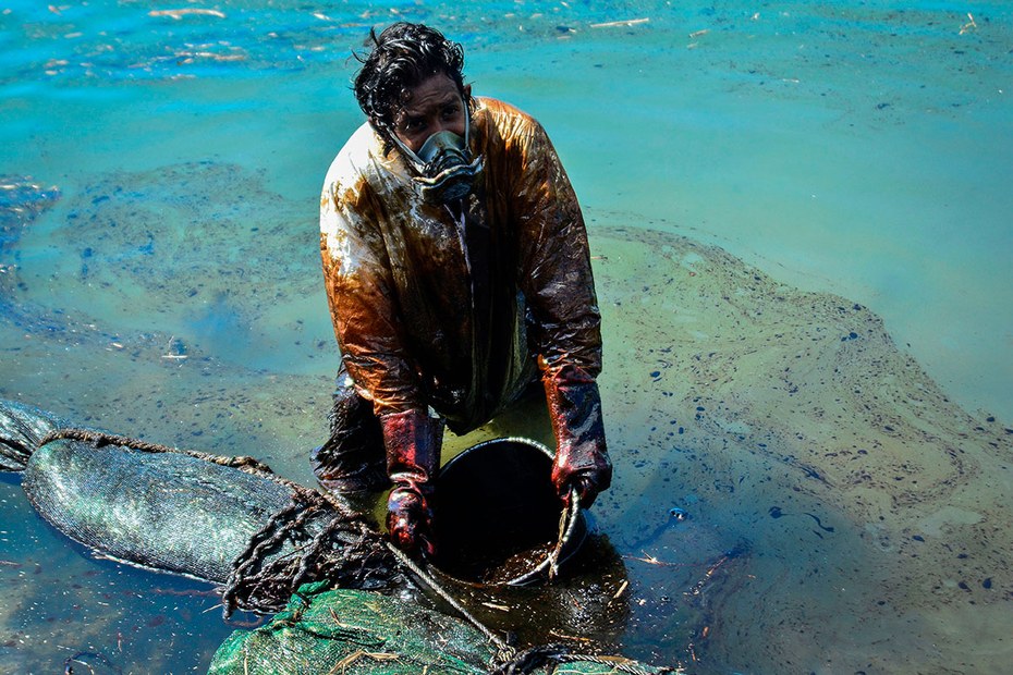 Ein Umweltschützer schöpft Öl aus dem Wasser vor der Küste von Mauritius