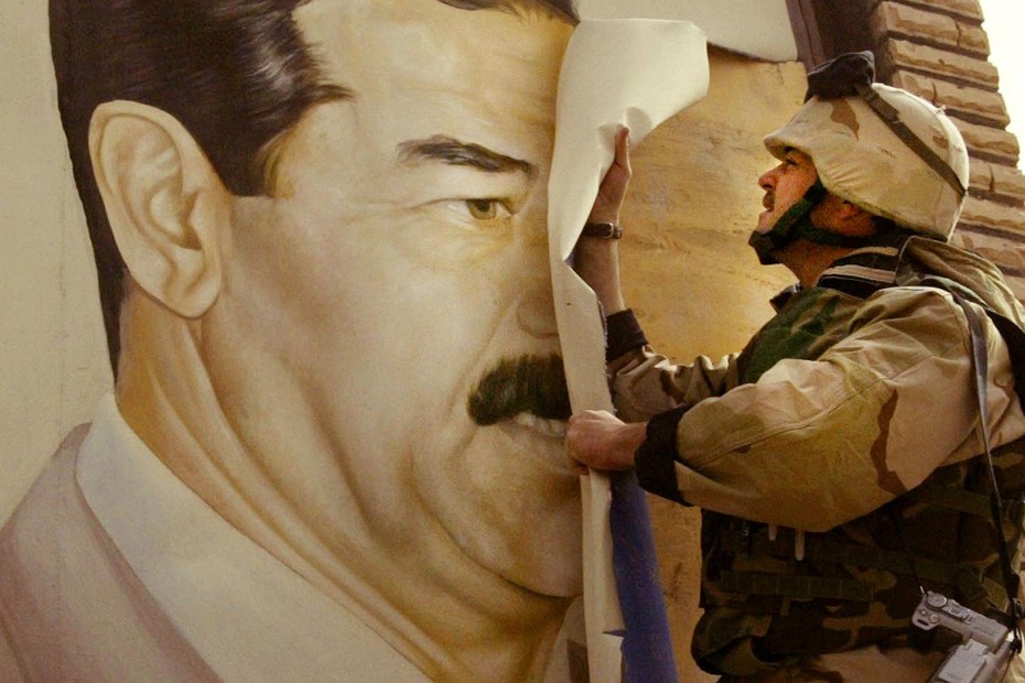 Ein US-Soldat reißt einen Tag nach Beginn des Krieges in Safwan im Südosten des Irak an der Grenze zu Kuwait ein Plakat mit Saddam Hussein von einer Fassade