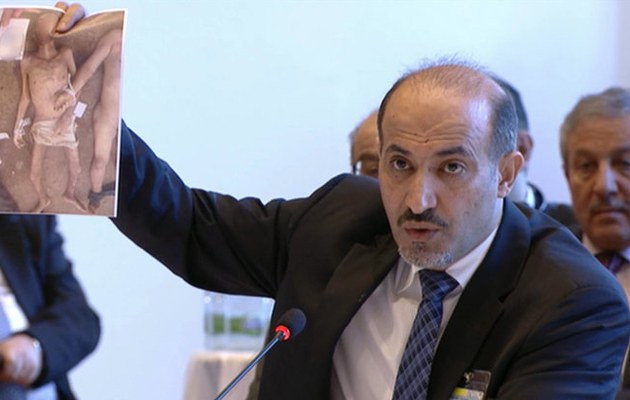 Der syrische Oppositionsführer Ahmed al-Dscharba zeigt während seiner Rede auf der Syrien-Konferenz in Genf Bilder der gefolterten Menschen