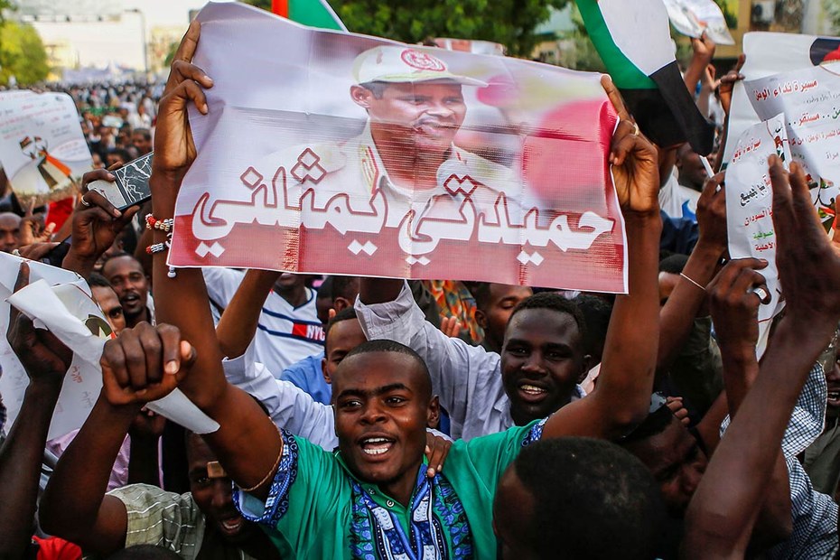 Ein Demonstrant hält ein Schild mit dem Porträt von Mohamed Hamdan Dagalo, genannt „Hemedti“. In der Unterzeile steht: „Hemedti steht für mich“