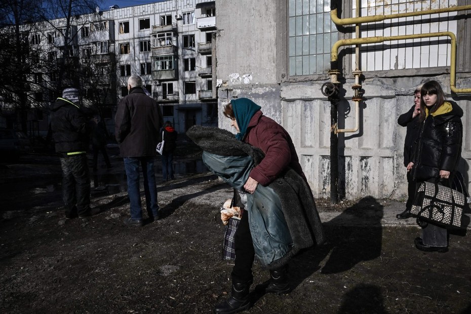 Menschen verlassen ein durch russische Angriffe zerstörtes Gebäude in der ost-ukrainische Stadt Tschuhujiw
