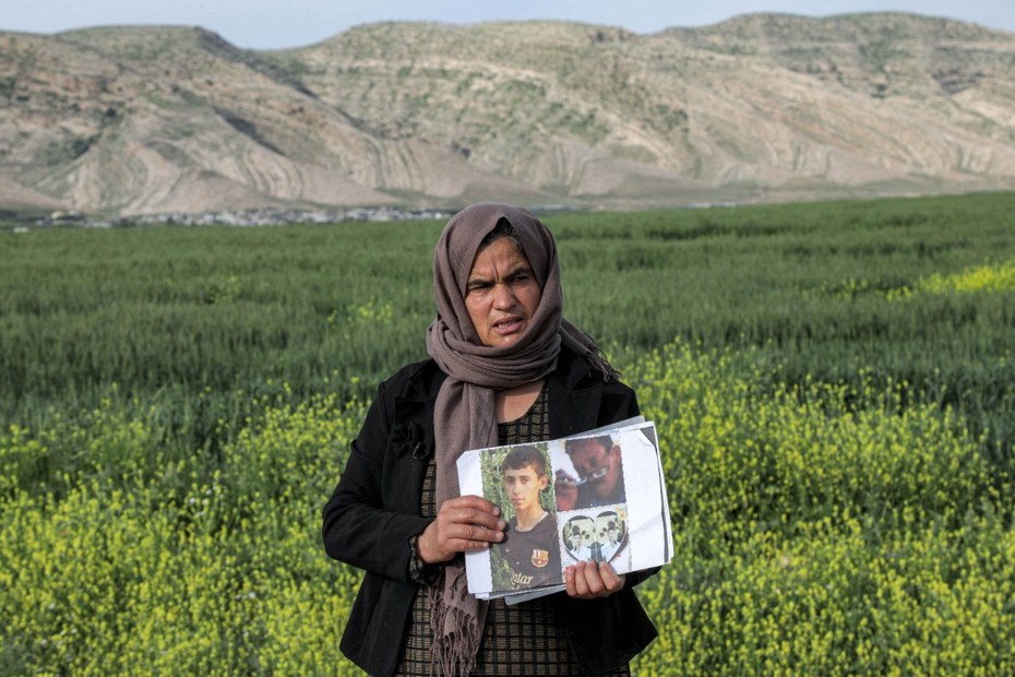 Eine Jesidin hält Bilder ihrer von Anhängern des IS entführten Familie in den Händen