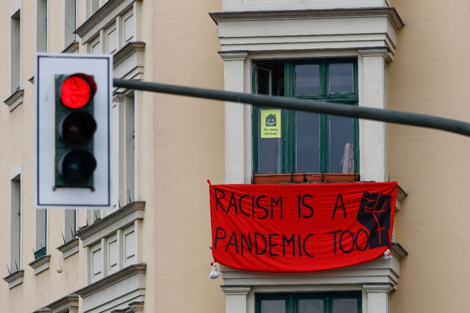 Ein Banner mit der Aufschrift „Rassismus ist auch eine Pandemie“ hängt aus einem Fenster eines Kreuzberger Haus zum 1. Mai 2021