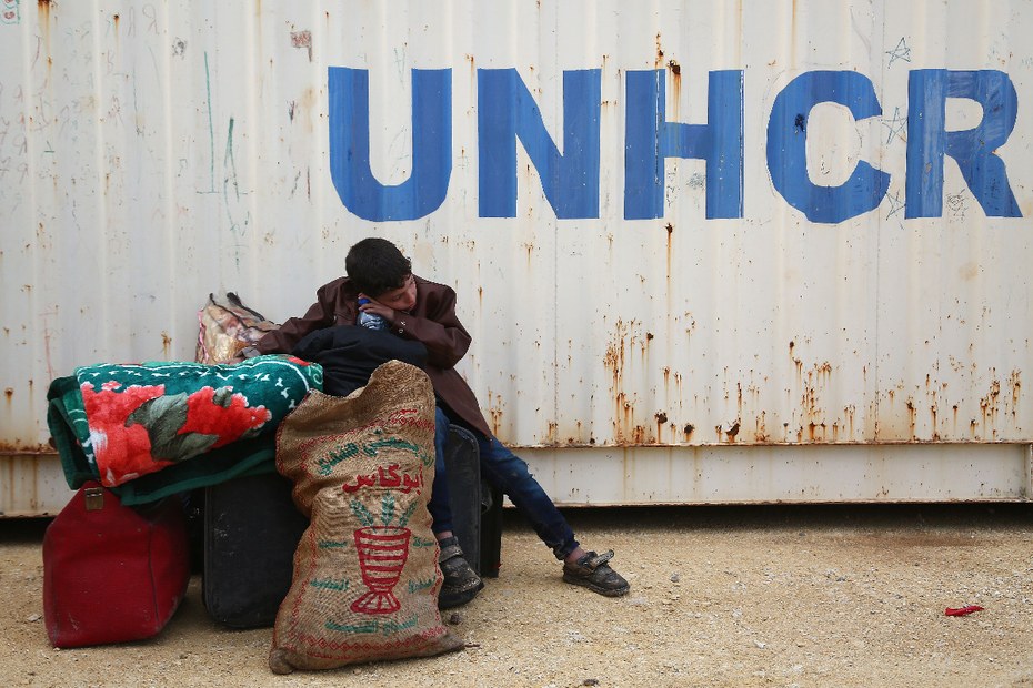 Ein syrischer Junge sitzt vor einem Flüchtlingscamp der UNHCR.