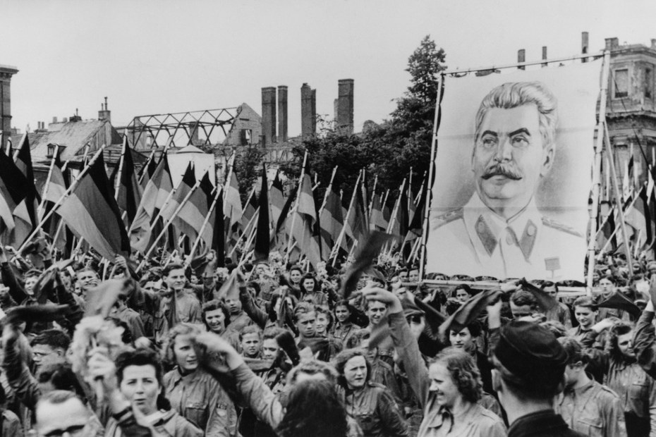 Anhänger:innen Josef Stalins halten im Rahmen einer Demonstration in der DDR ein Banner mit seinem Porträt hoch (1950)