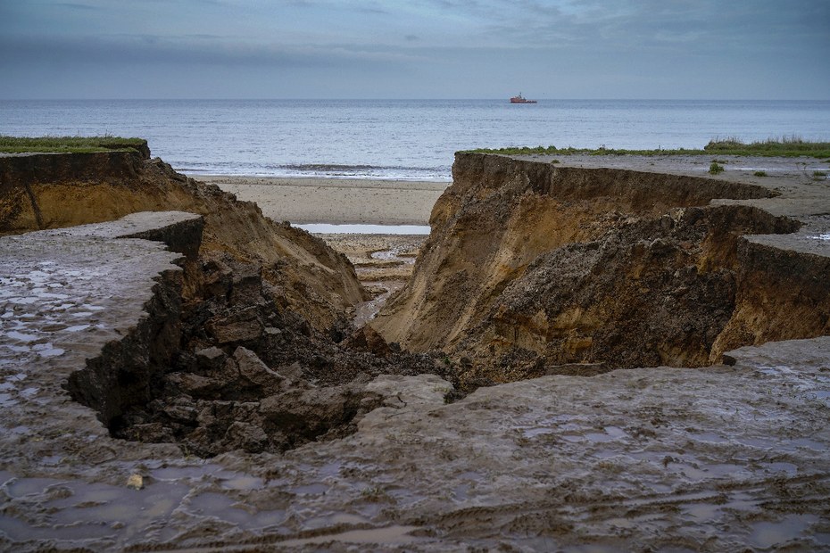 Erosionen von Sanddünen in Norfolk haben dazu geführt, dass viele Gebäude und Ackerland an das Meer verloren gegangen sind. Die Auswirkungen des globalen Klimawandels, der Stürme und Seegang verursacht, haben dazu geführt, dass die Ostküste des Vereinigten Königreichs jedes Jahr bis zu einem Meter an Küstenlinie verliert.