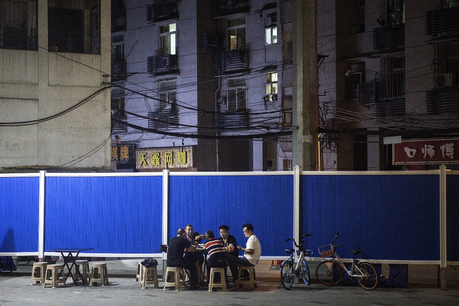 Bewohner essen neben einer provisorischen Barrikade, die errichtet wurde, um die Ein- und Ausfahrt in eine Wohnanlage zu kontrollieren, zu Abend.