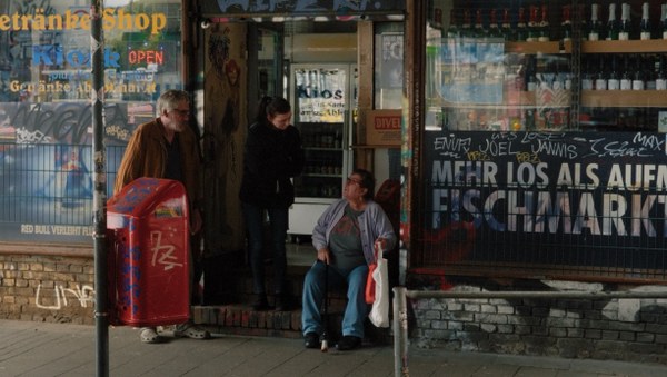 Drei Personen sitzen vor einem Kiosk an der Sternbrücke Hamburg.