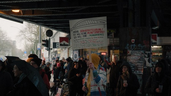 Eine Demonstration bei der Sternbrücke Hamburg. Ein Demonstrant hält ein Schild hoch auf dem steht: „Mehr Bürgerbeteiligung. Ich will keine Monsterbrücke! Ich will eine Mondbrücke!“