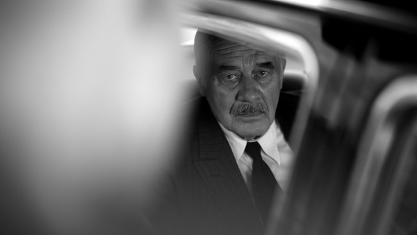Thomas Mann (Hanns Zischler) sitzt in seinem Auto und schaut in die Kamera.